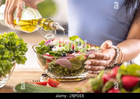 Die letzte Zubereitung eines gesunden Salats und am Ende gießt die Frau Olivenöl ein. Stockfoto