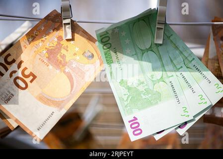 Eine Nahaufnahme von fünfzig und hundert Euro-Banknoten, die an einer Kleiderschnur hängen Stockfoto