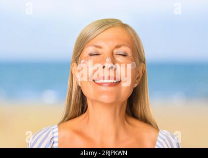 Sonnenschutz. Schöne junge Frau mit Sonnencreme auf ihrem Gesicht in der Nähe des Meeres Stockfoto