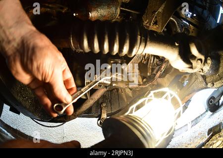 Mechaniker, der Inspektionslampen verwendet, die unter dem Fahrzeug arbeiten Stockfoto