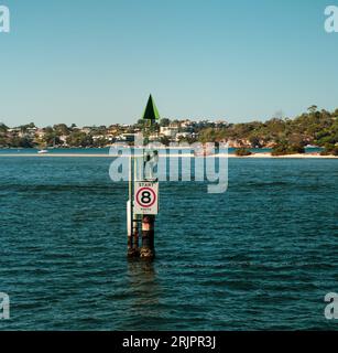 Ein Wegweiser am Ende eines hölzernen Pier, der sich in die weite Weite des offenen Ozeans erstreckt Stockfoto