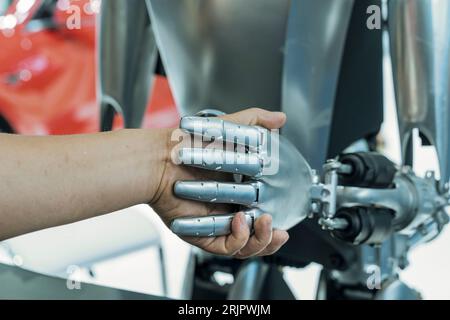 Eine menschliche Hand, die mit einem Roboter die Hände schüttelt - das Konzept der menschlichen Interaktion mit künstlicher Intelligenz Stockfoto