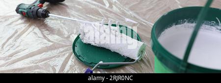 Lackmischer mit weißem Lackeimer und Bürstenrolle auf dem Boden. Stockfoto