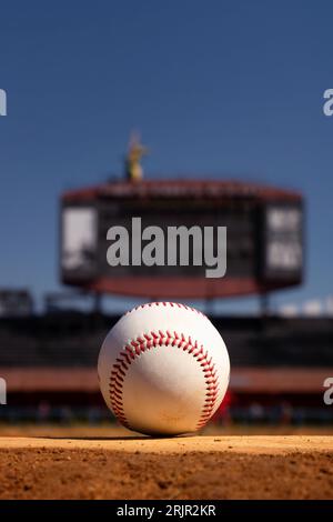 Ein weißer Baseball, der sich auf einer regulatorischen Heimplatte in einem leeren Sportstadion ruht, bereit für ein Spiel Stockfoto