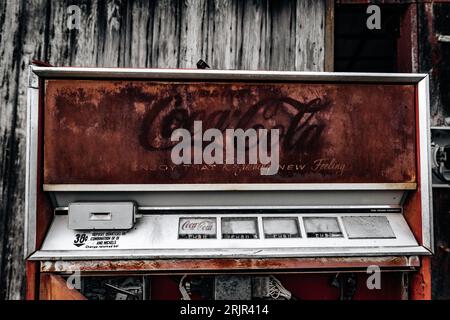 Ein kultiger roter Coca-Cola-Automat vor einem alten, verwitterten Gebäude, der einen zeitlosen und klassischen Look kreiert Stockfoto