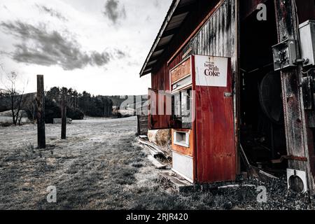 Ein kultiger roter Coca-Cola-Automat vor einem alten, verwitterten Gebäude, der einen zeitlosen und klassischen Look kreiert Stockfoto