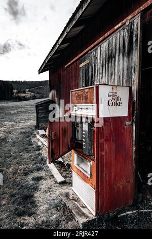 Ein kultiger roter Coca-Cola-Automat vor einem alten, verwitterten Gebäude, der einen zeitlosen und klassischen Look kreiert Stockfoto