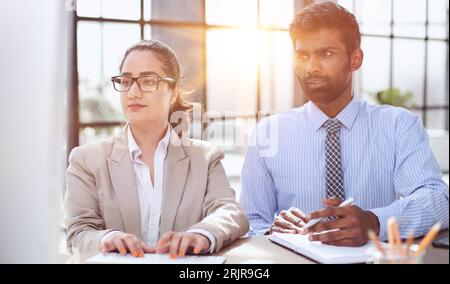 Junge indische Mentorentrainerin, die mit einer Kollegin spricht, die eine Trainee unterrichtet, und mit einer Arbeitskollegin ein Geschäftsgespräch führt Stockfoto