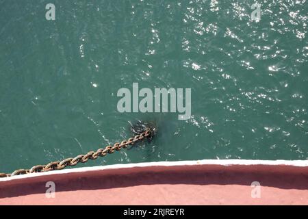 Ein Blick von oben auf einen metallischen Anker, der von einem Schiff hängt Stockfoto