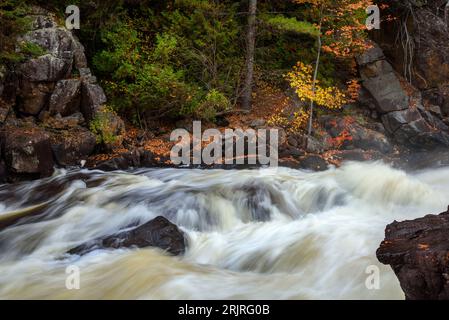 Fast flowing water near a waterfall along a mountain river in autumn Stock Photo