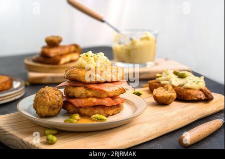 Ein frisch zubereiteter Hackbraten-Burger, der auf einem rustikalen Holztisch serviert wird und von Gewürzen umgeben ist Stockfoto