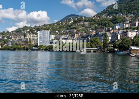 Der Genfer See mit einer malerischen Küste mit einer Vielzahl von leuchtend grünen Bäumen und atemberaubenden Gebäuden Stockfoto