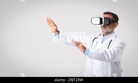 Positiver kaukasischer Senior Doctor Therapist in weißem Fell und vr-Brille kontrolliert Leerraum Stockfoto