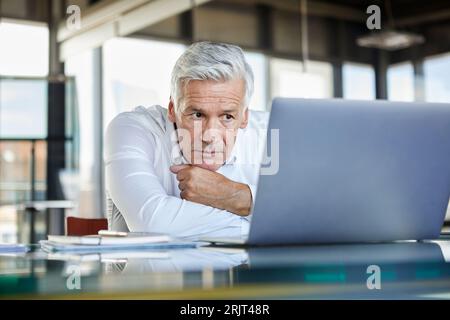 Geschäftsmann am Schreibtisch sitzen und versuchen, ein Problem zu lösen Stockfoto