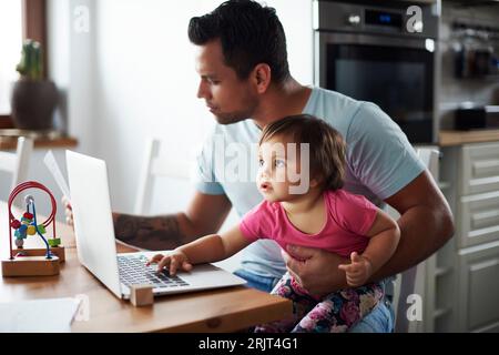 Vater mit Baby Mädchen mit Laptop auf dem Tisch zu Hause Stockfoto