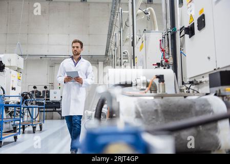 Mitarbeiter Kontrolle der Fertigung Maschinen in High Tech Unternehmen, indem Sie digitale Tablet Stockfoto