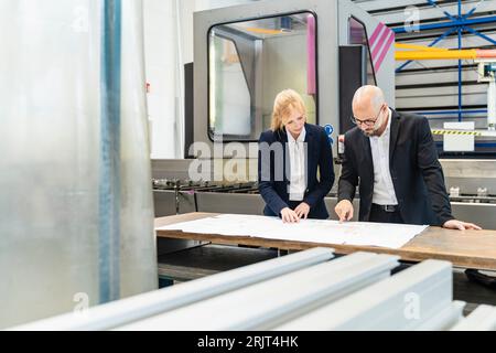 Kaufmann und Kauffrau auf der Suche nach Plan auf dem Tisch in der Factory Stockfoto