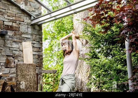 Schreiende Frau holzhacken vor einem Haus Stockfoto