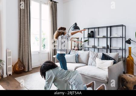 Glückliche Eltern spielen mit ihrer Tochter im Wohnzimmer den Buff eines blinden Mannes Stockfoto