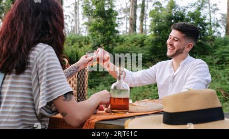 Ein fröhliches junges Paar, das im Wald einen Drink genießt Stockfoto