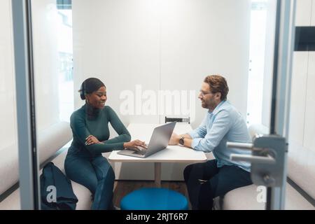 Glückliche junge Geschäftsfrau, die mit dem Kunden im Büro spricht Stockfoto