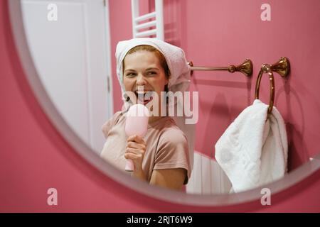 Frau, die die Haarbürste hält und im Badezimmer singt Stockfoto