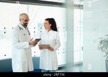 Glückliche Ärzte, die über Tablet-PC im Krankenhaus diskutieren Stockfoto