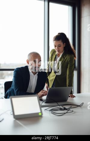 Reifer Geschäftsmann und Geschäftsfrau, die über Laptop diskutieren Stockfoto