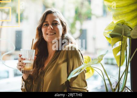Lächelnde Frau mit einem Glas Saft im Café Stockfoto