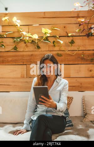 Glückliche junge Geschäftsfrau, die Tablet-PC auf dem Sofa im Büro verwendet Stockfoto