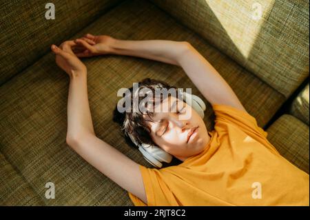 Teenager, der Kopfhörer auf dem Sofa trägt Stockfoto