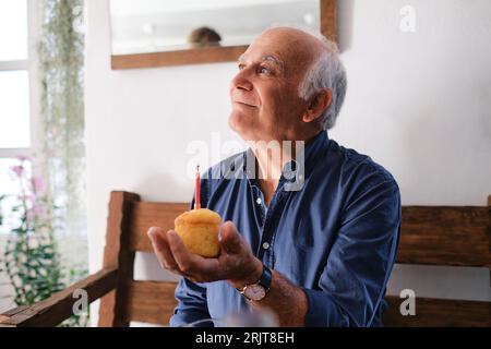 Lächelnder Seniormann, der Cupcake hält Stockfoto