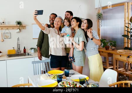 Lächelnde Familie nimmt Selfie mit Smartphone in der Küche Stockfoto