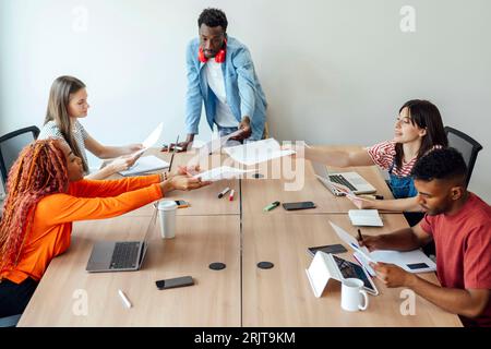 Geschäftsmann, der mit Kollegen über Dokumente diskutiert Stockfoto