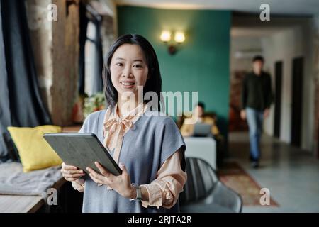 Selbstbewusste junge Geschäftsfrau, die einen Tablet-PC im Café hält Stockfoto