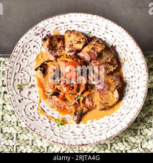 Eine Draufsicht auf einen Teller mit saftigen Rindfleischscheiben in einer Sauce Stockfoto