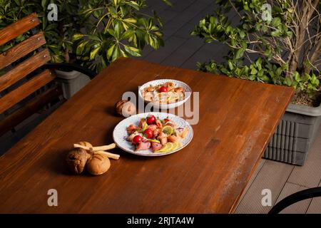 Ein kleiner Salat mit Lachs und Kirschtomate und ein Teller mit Shrimps auf einem Holztisch Stockfoto