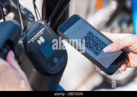 Hände einer Frau, die ein Elektrofahrrad über die Handy-App mietet Stockfoto