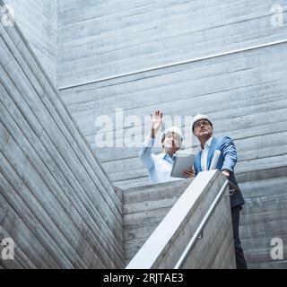 Gesten des Architekten und Gespräch mit Kollegen auf der Treppe Stockfoto