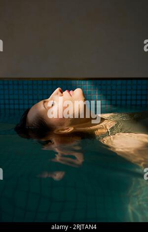 Wunderschöne Frau, die im Whirlpool im Spa schwimmt Stockfoto