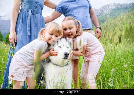 Niedliche Schwestern, die einen Hund auf Gras umarmen Stockfoto