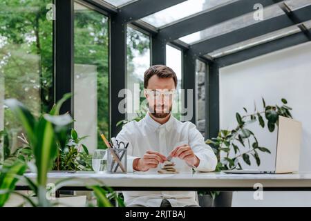 Geschäftsmann stapelt Kieselsteine am Schreibtisch im Büro Stockfoto