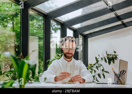 Lächelnder Geschäftsmann, der Kieselsteine am Schreibtisch im Büro stapelt Stockfoto