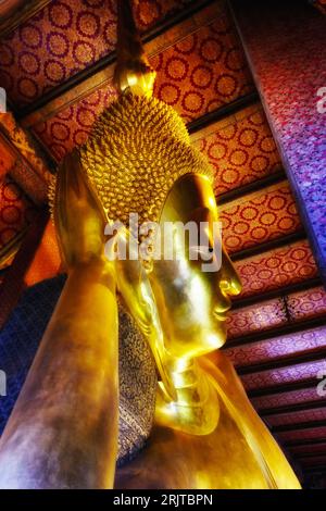 The detailed artistry of a gilded Buddha face from the Temple of the Reclining Buddha in Bangkok is unveiled in this close-up. Stock Photo