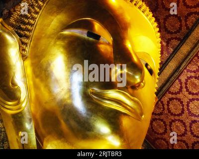 Ein vergoldetes Buddhagesicht aus dem thailändischen Tempel des liegenden Buddhas in Bangkok, Nahaufnahme. Stockfoto