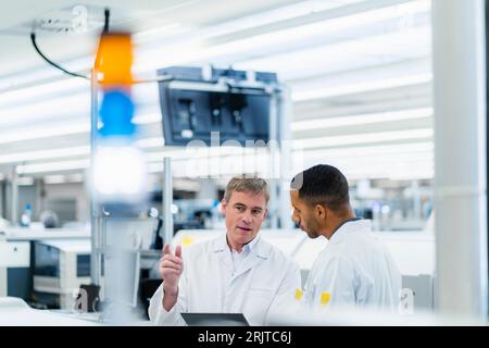 Techniker in Labormänteln diskutieren in der Elektronikfabrik Stockfoto