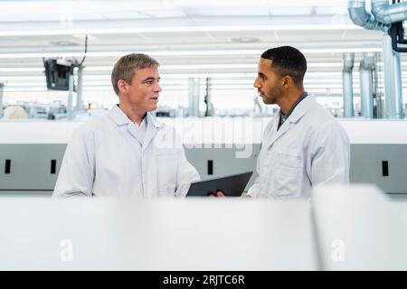 Team von kompetenten Elektrotechnikern in Labormänteln, das sich in der Elektronikfabrik trifft Stockfoto