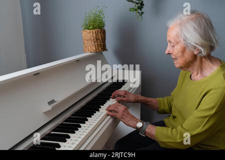 Seniorin spielt zu Hause Klavier Stockfoto
