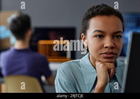 IT-Profi mit der Hand auf dem Kinn, der im Büro arbeitet Stockfoto
