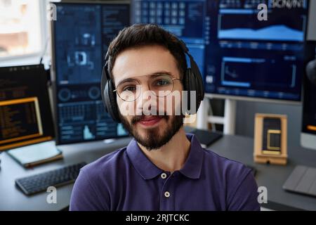 Lächelnd, professionell, mit kabellosen Kopfhörern vor dem Computer Stockfoto